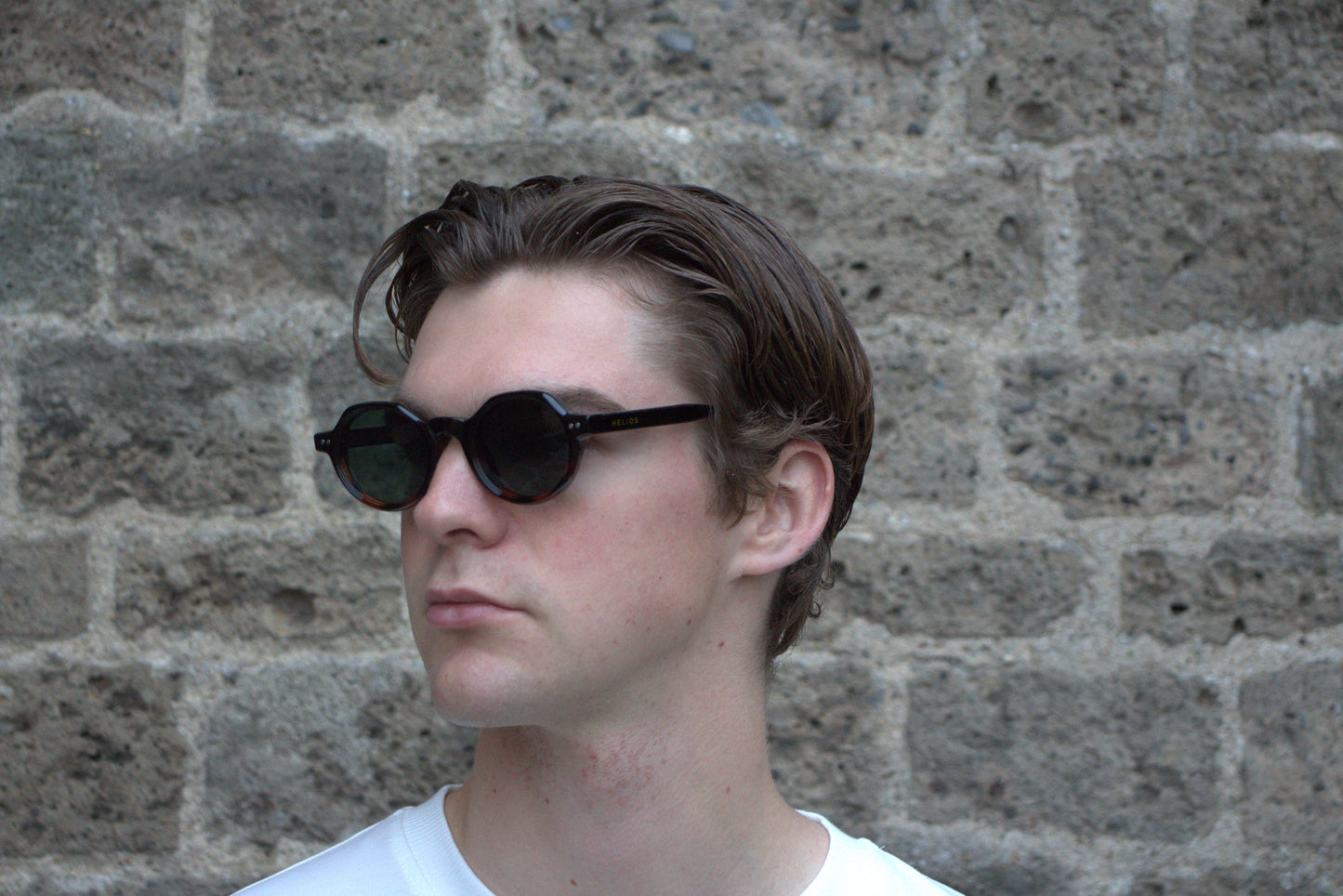 Person wearing sunglasses with a stone wall background
