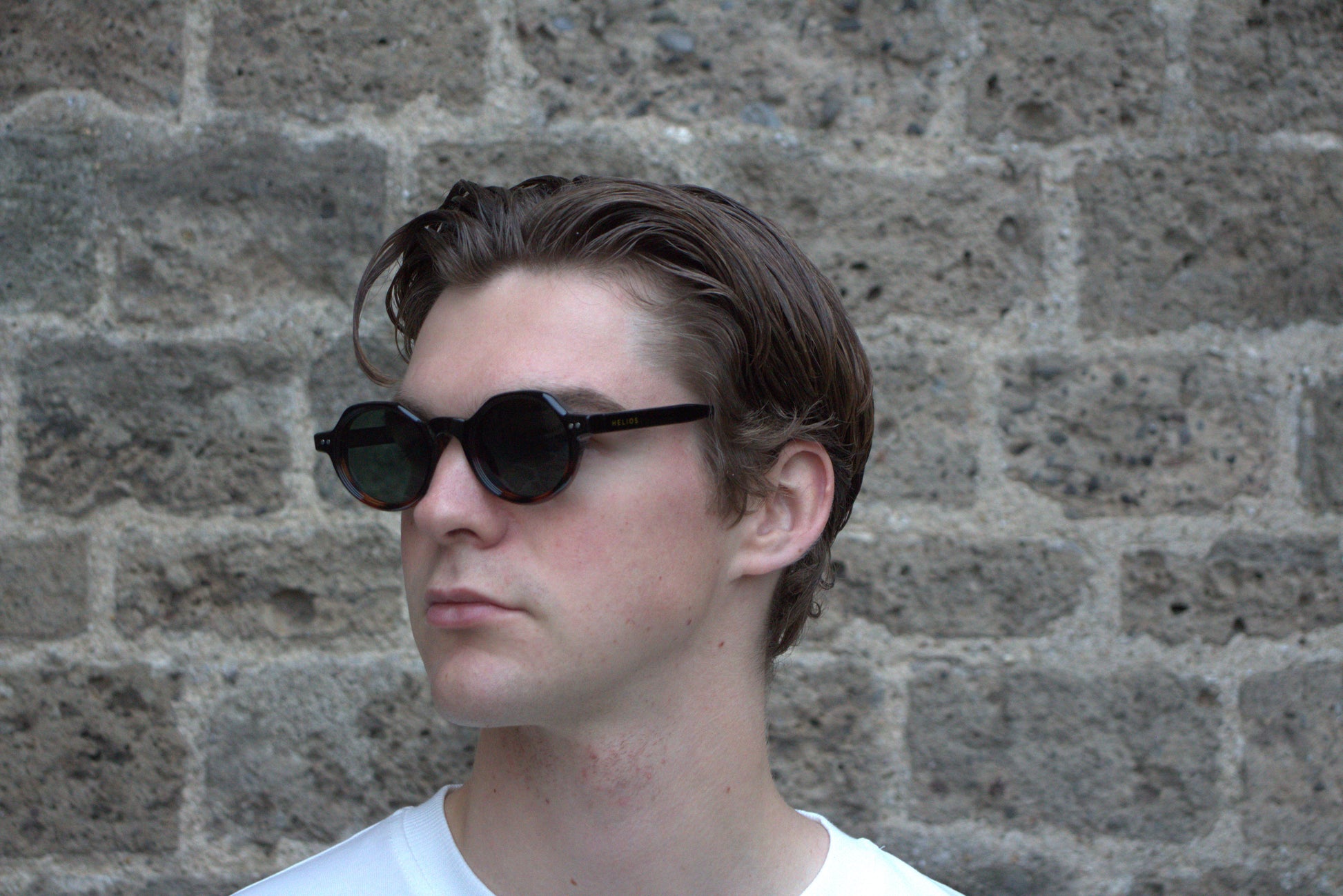Person wearing sunglasses with a stone wall background