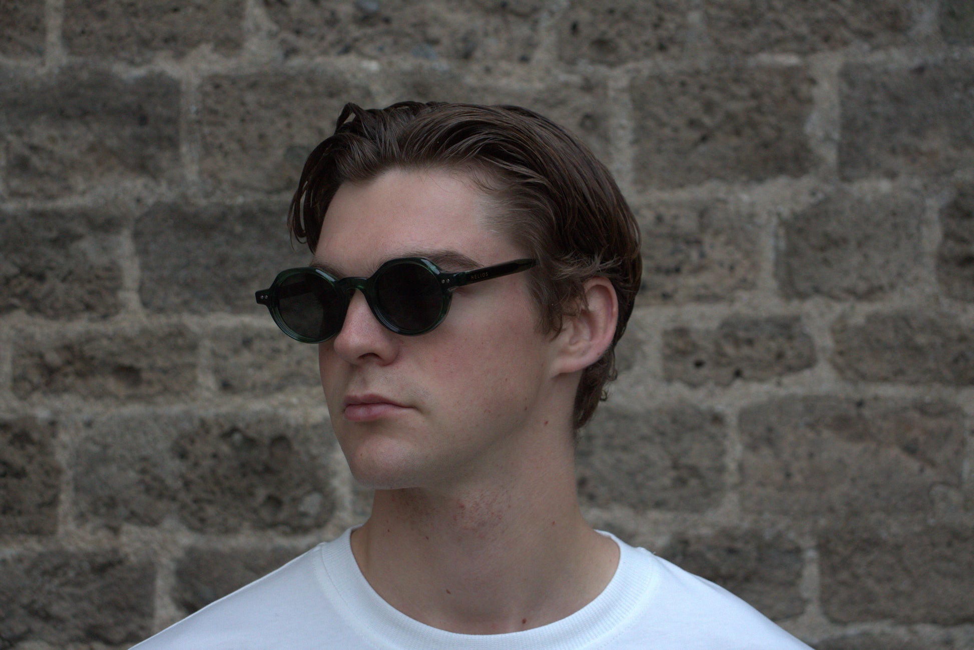Person wearing sunglasses with a stone wall background