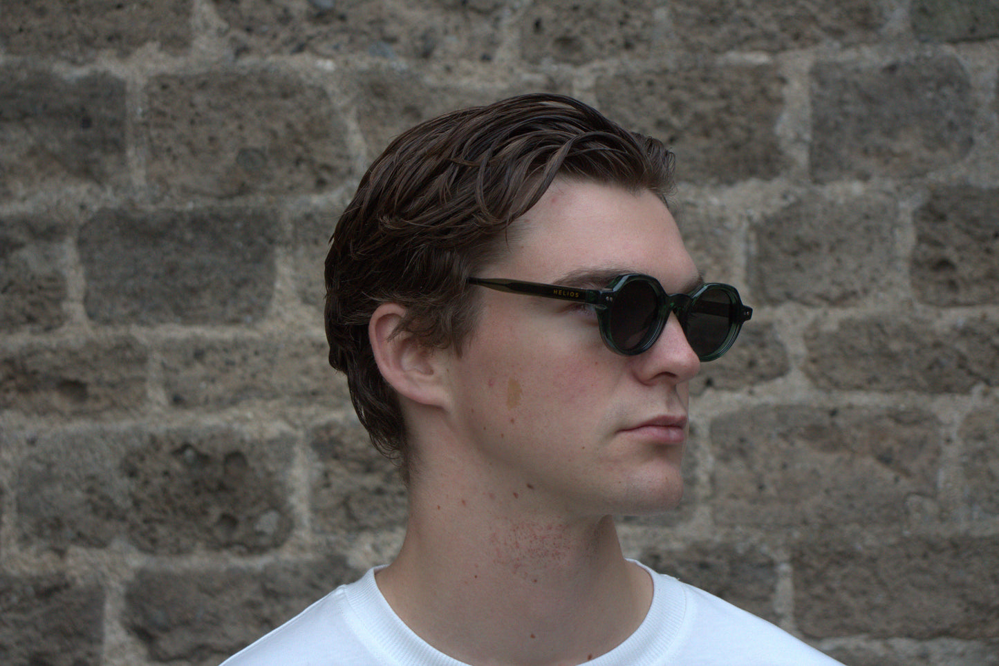 Man wearing sunglasses with a brick wall background