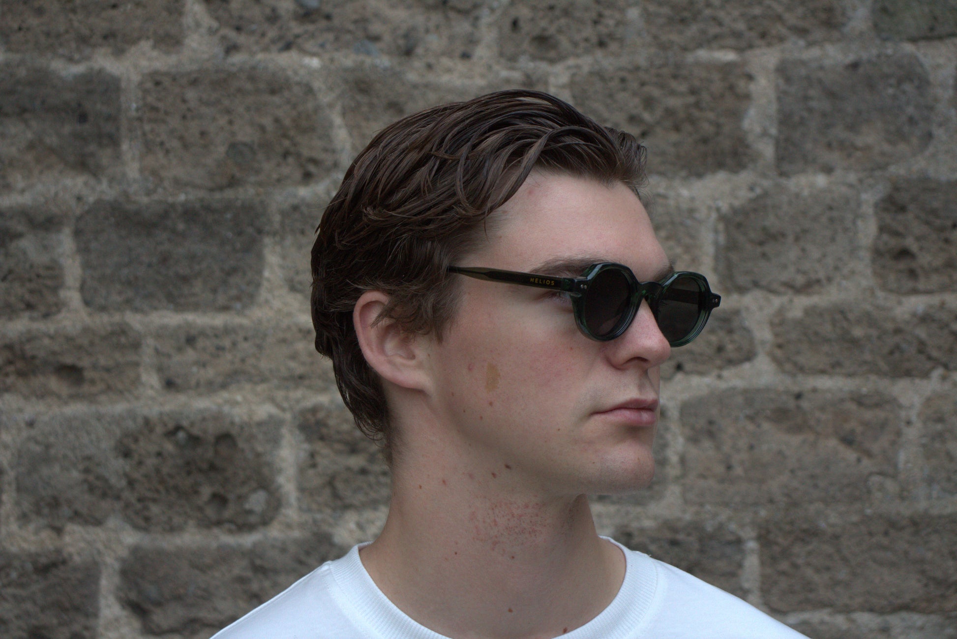 Man wearing sunglasses with a brick wall background