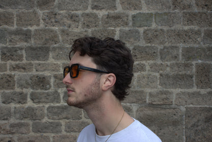 Man wearing sunglasses with a brick wall background