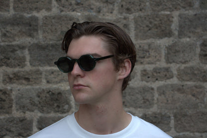 Person wearing sunglasses with a stone wall background