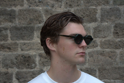 Man wearing sunglasses with a brick wall background